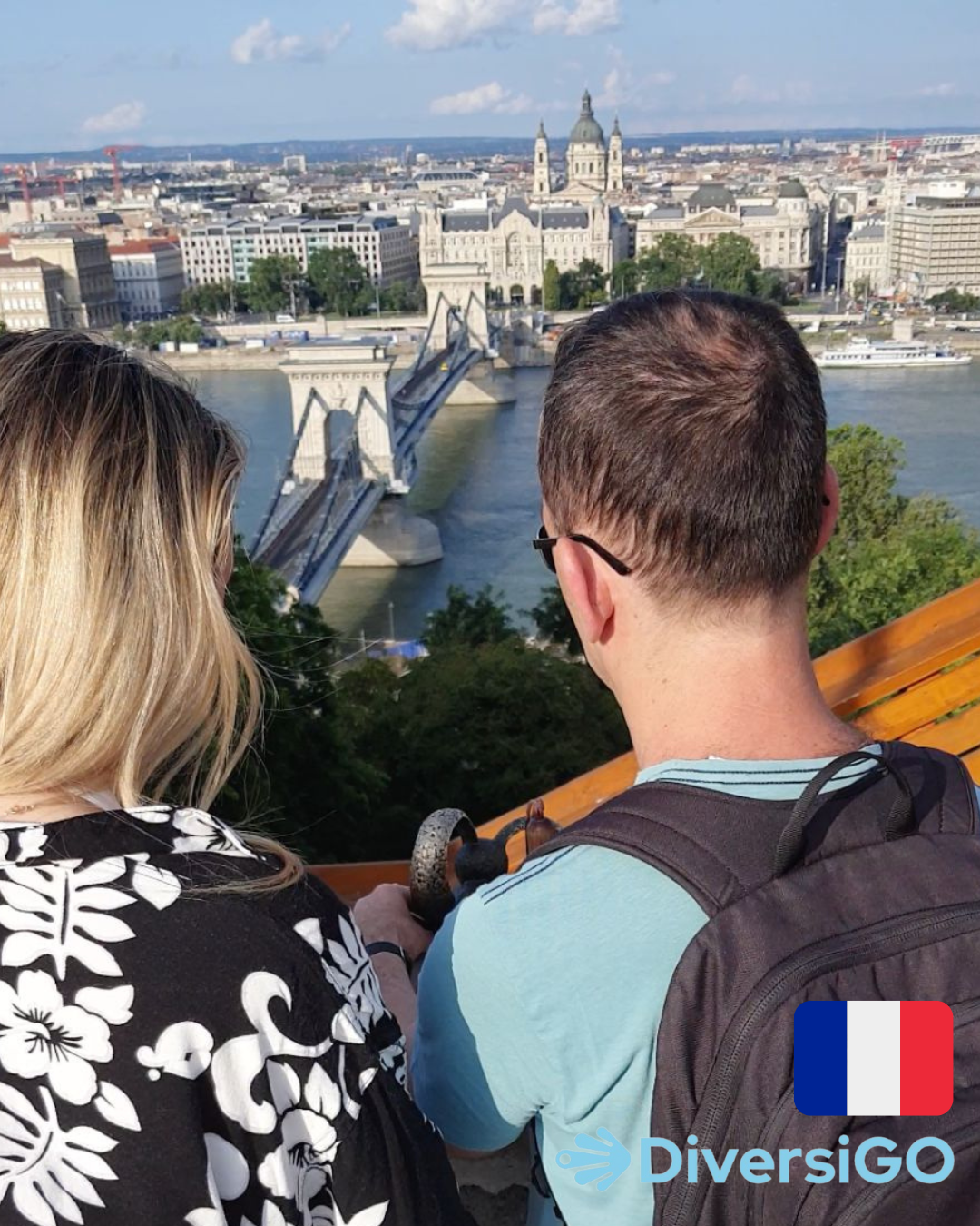 Le guide touristique de DiversiGO montre à un touriste la minisculpture tactile d'un célèbre personnage de dessin animé hongrois, "Le lapin aux oreilles à carreaux", à un endroit où il y a une vue panoramique de Budapest avec le Danube.