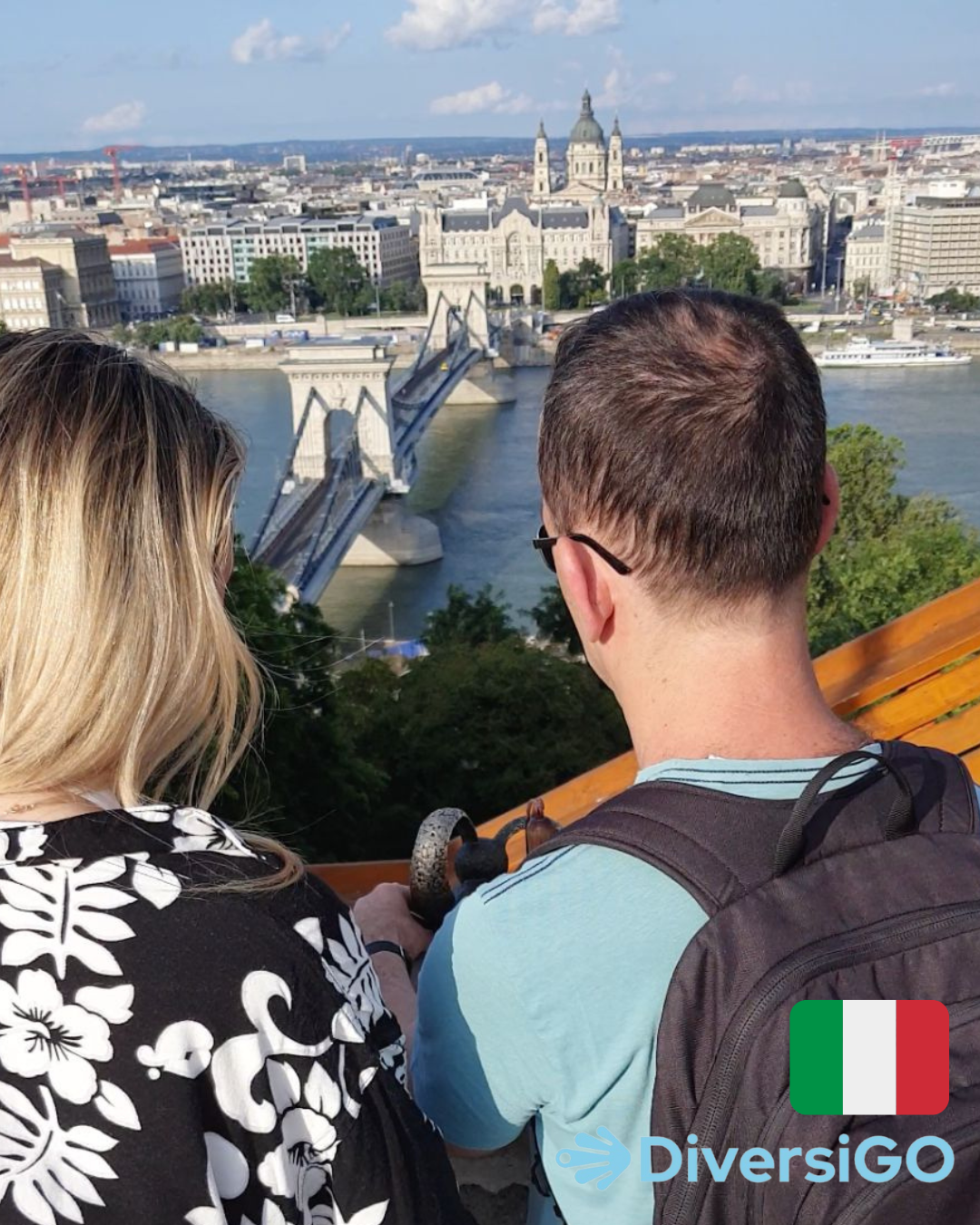 La guida turistica di DiversiGO mostra a un turista la mini-scultura tattile di un famoso personaggio dei cartoni animati ungherese, "Il coniglio dalle orecchie a scacchi", in un punto da cui si gode una vista panoramica di Budapest con il Danubio.