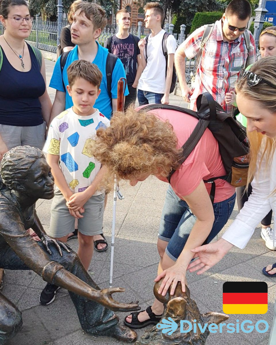 Der Reiseleiter von DiversiGO hilft den Touristen, die lebensechte, taktile Statue eines Mädchens zu beobachten, das mit ihrem Hund spielt.