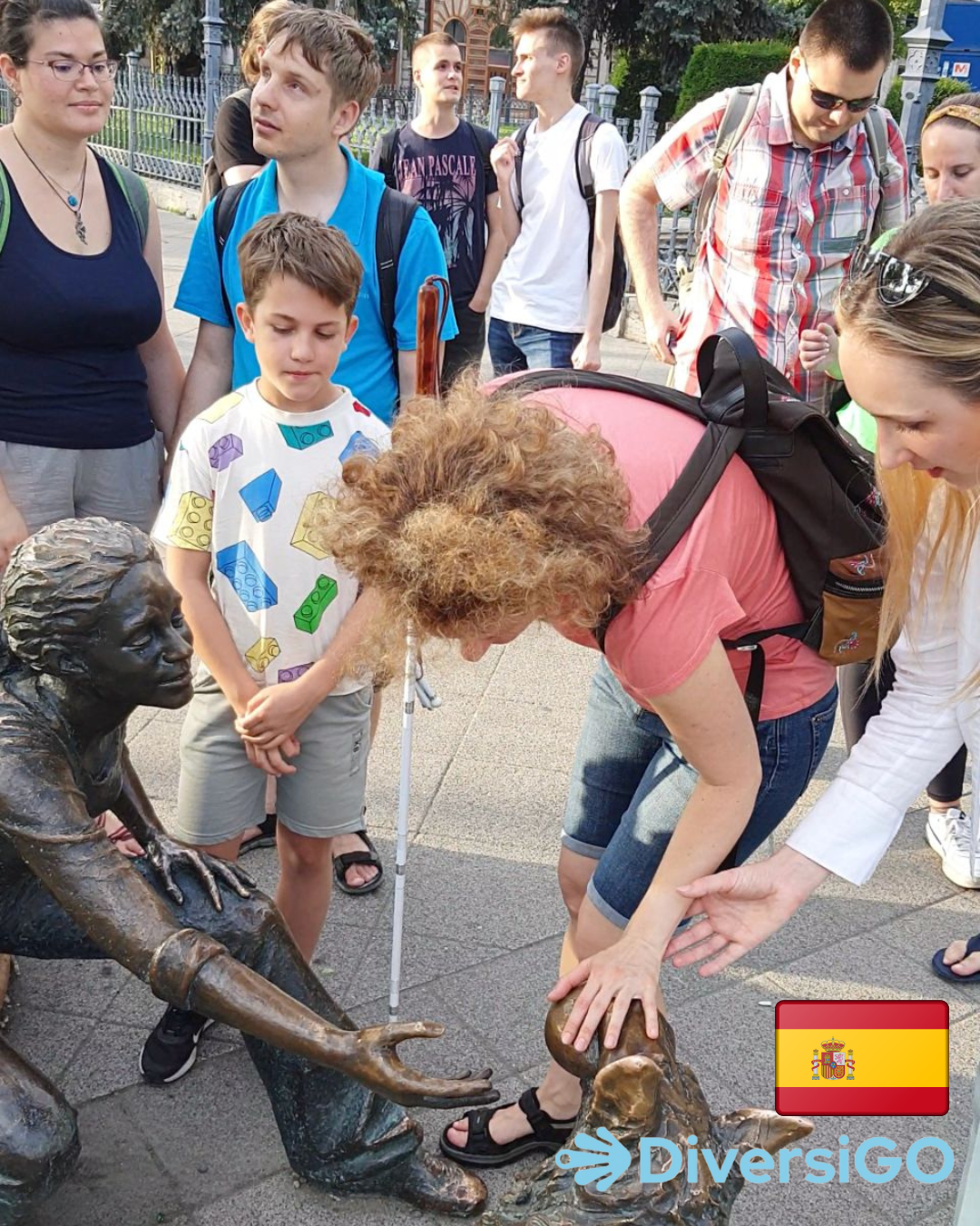 El guía de DiversiGO ayuda a los turistas a observar la estatua táctil de una niña jugando con su perro.