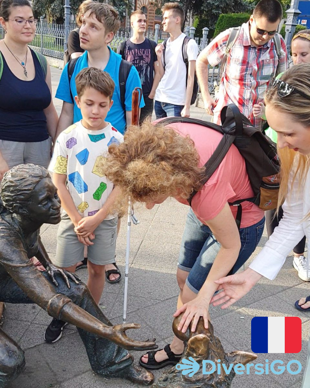 Le guide de DiversiGO aide les touristes à observer la statue tactile réaliste d'une fille jouant avec son chien.